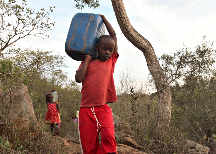To barn bærer kanner med vann. Foto: Bjørn-Owe-Holmberg
