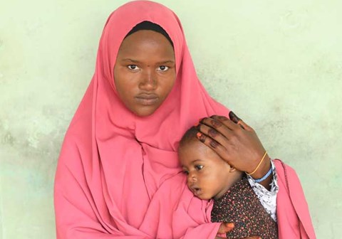 Anab, 28 år, i rosa hijab holder den lille datteren i tett inntil seg. Datteren var akutt underernært og har fått hjelp ved et av SOS-barnebyers medisinske sentre. Foto: Sunshine Media