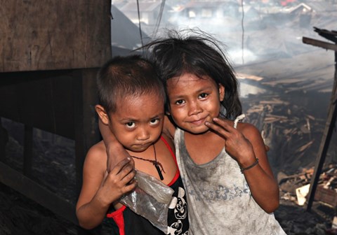 Et søskenpar, en liten gutt og ei lita jente står på søppeldynga i slummen. Foto: Bjørn-Owe Holmberg