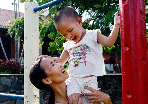 En same løfter opp et barn i Vietnam.