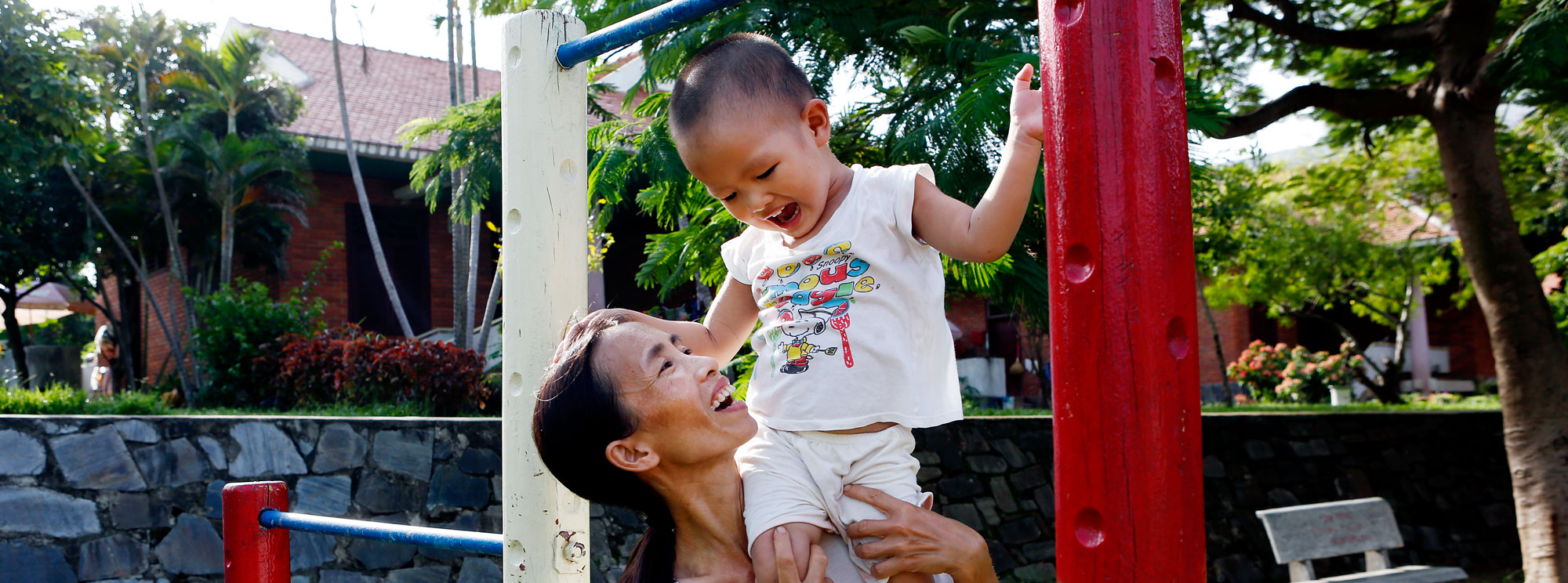 En same løfter opp et barn i Vietnam.