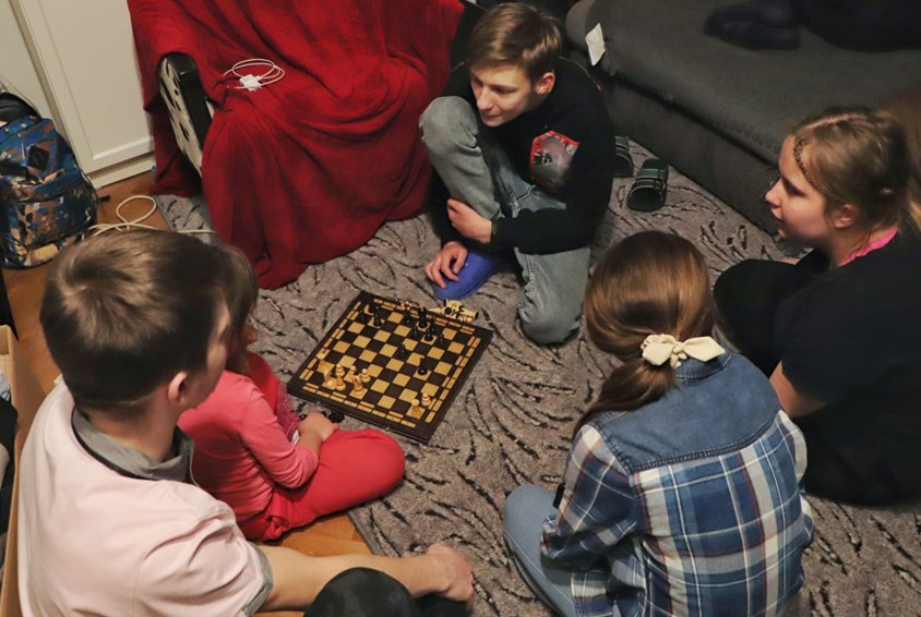 Fem barn fra SOS-barnebyer i Ukraina er nå i trygghet i en barneby i Polen, de sitter på gulvet og spiller sjakk. Foto: SOS-barnebyer