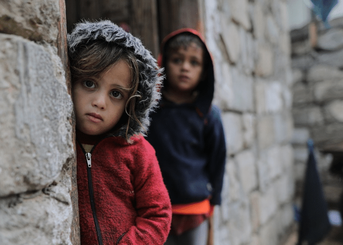 To barn står ved en murvegg og ser inn i kamera i Gaza, 2023. Fotograf: Salah Hosny