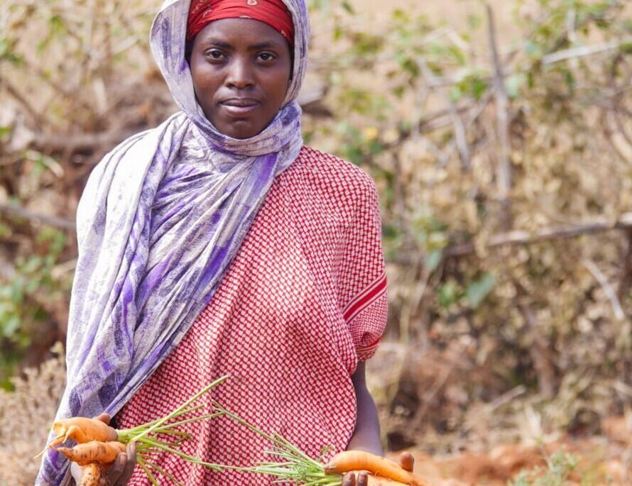 Amina i Etiopia holder nyhøstede gulrøtter i hendene