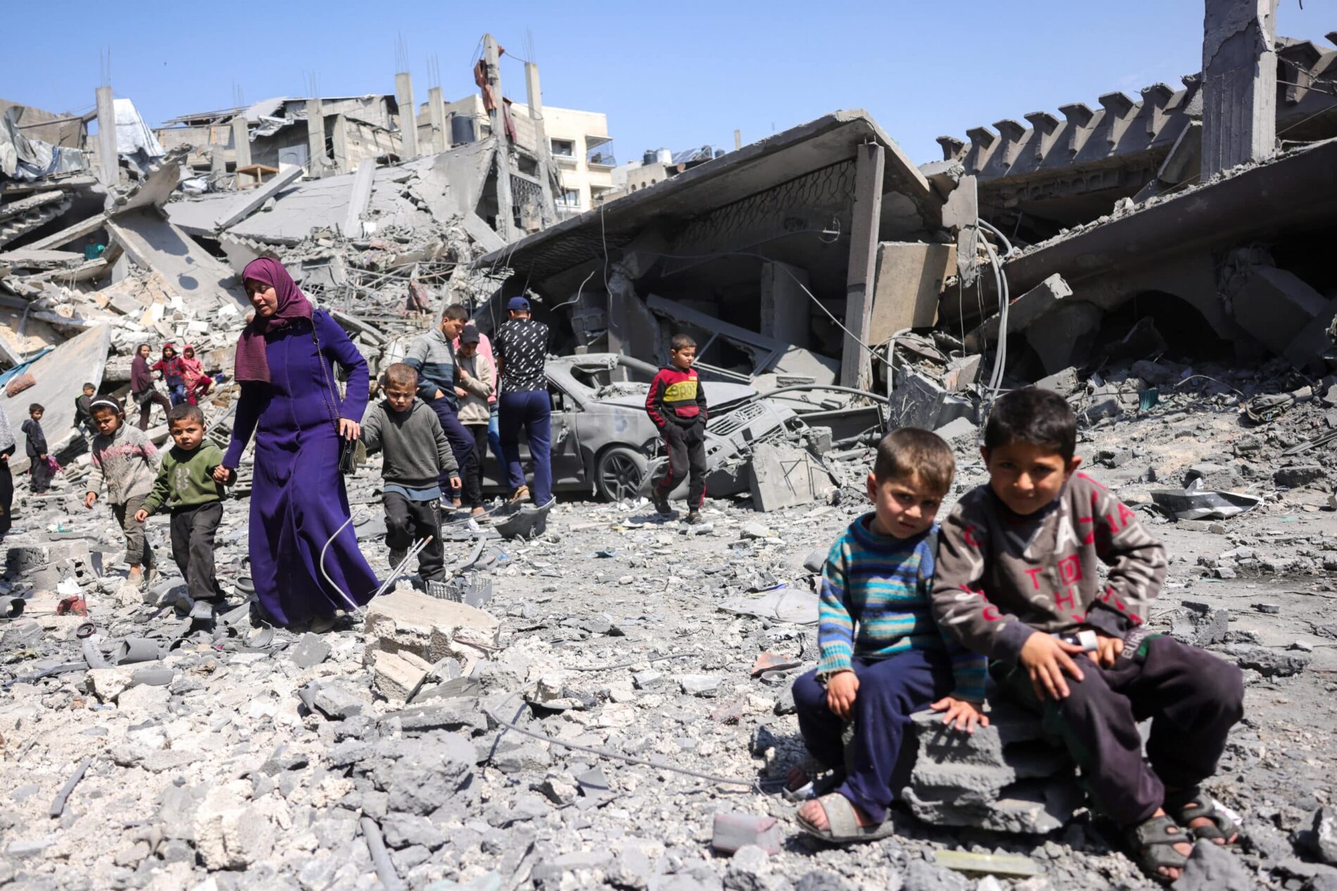 Barn ser på mens folk går blant ruinene av en bygning som ble ødelagt i et israelsk angrep natt til 18. mars 2025 i Jabalia, nord i Gazastripen. Foto: Bashar TALEB / AFP