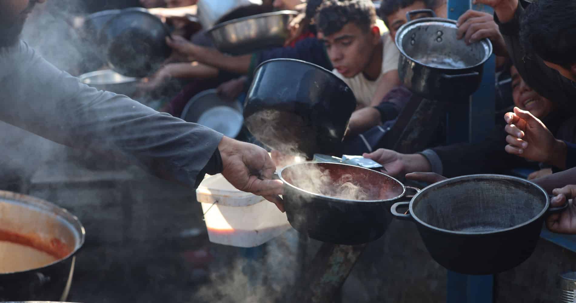 Mange vokse og barn strekker fram hendene med skåler for å få mat. Foto Mohammad AlBaba