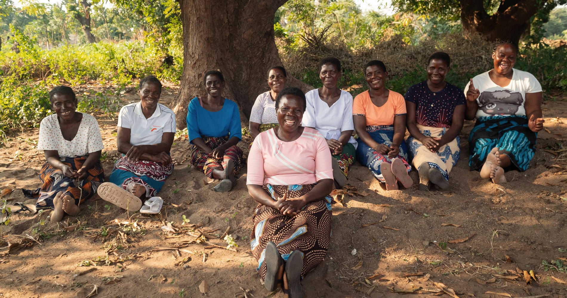 Mange kvinner fra Malawi sitter på bakken i skyggen av et tre. Foto Cornelis van Heerden