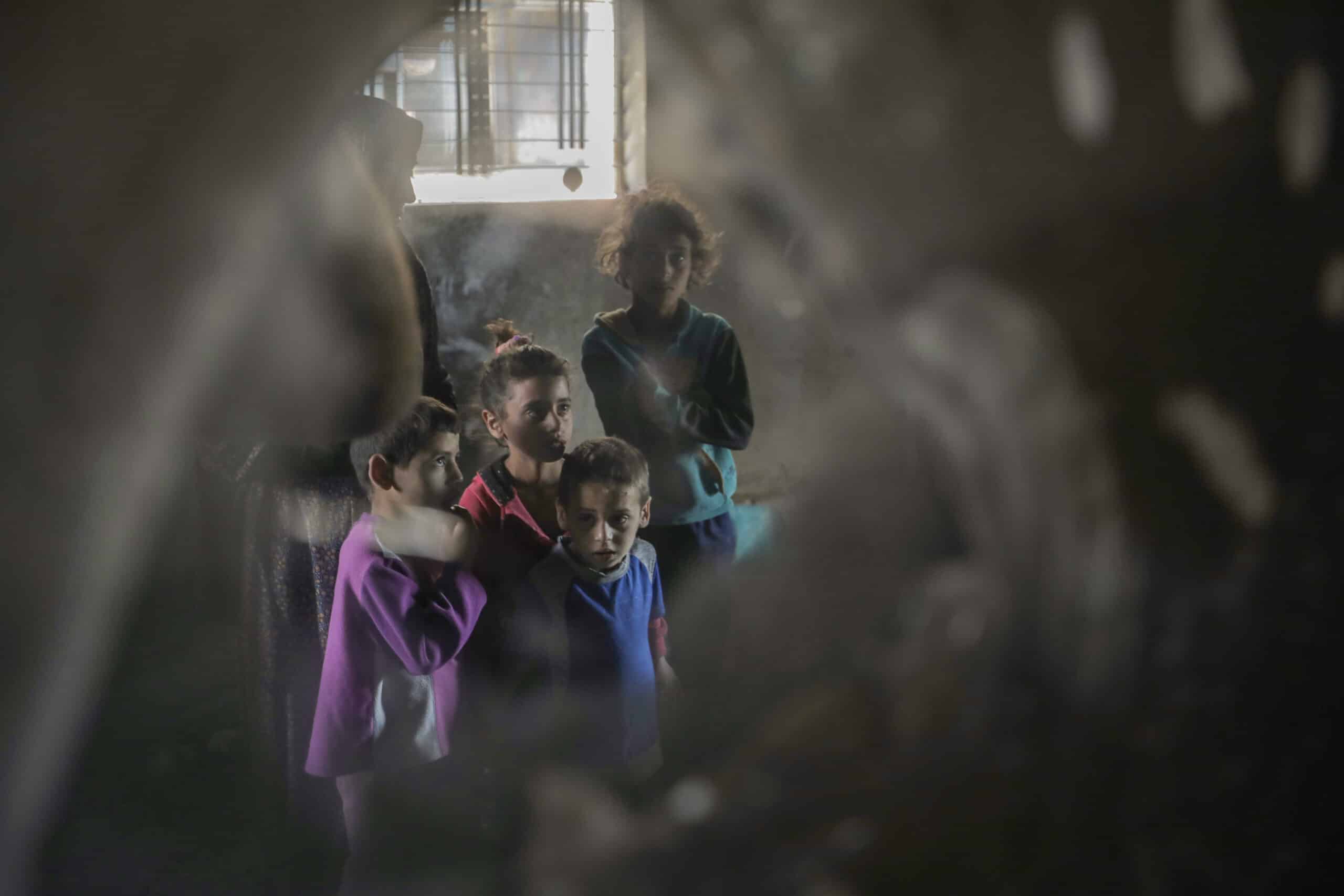 En gruppe barn står samlet i et dunkelt rom i Gaza, og ser alvorlig mot kamera.