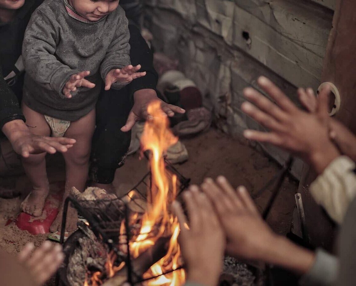 Barn varmer seg rundt et bål i Gaza. Fotograf: Hosny Salah. Bli SOS-fadder