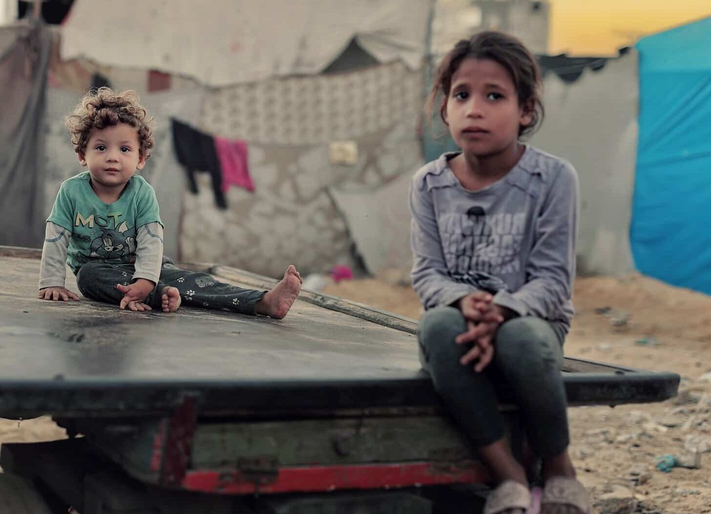 Søsken sitter på ett lasteplan i Gaza. Liten gutt og storesøster.