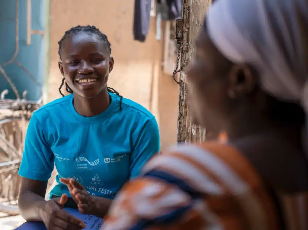 En sosialarbeider snakker med en en omsorgsperson i SOS-barnebyers forebyggende program i Ghana.