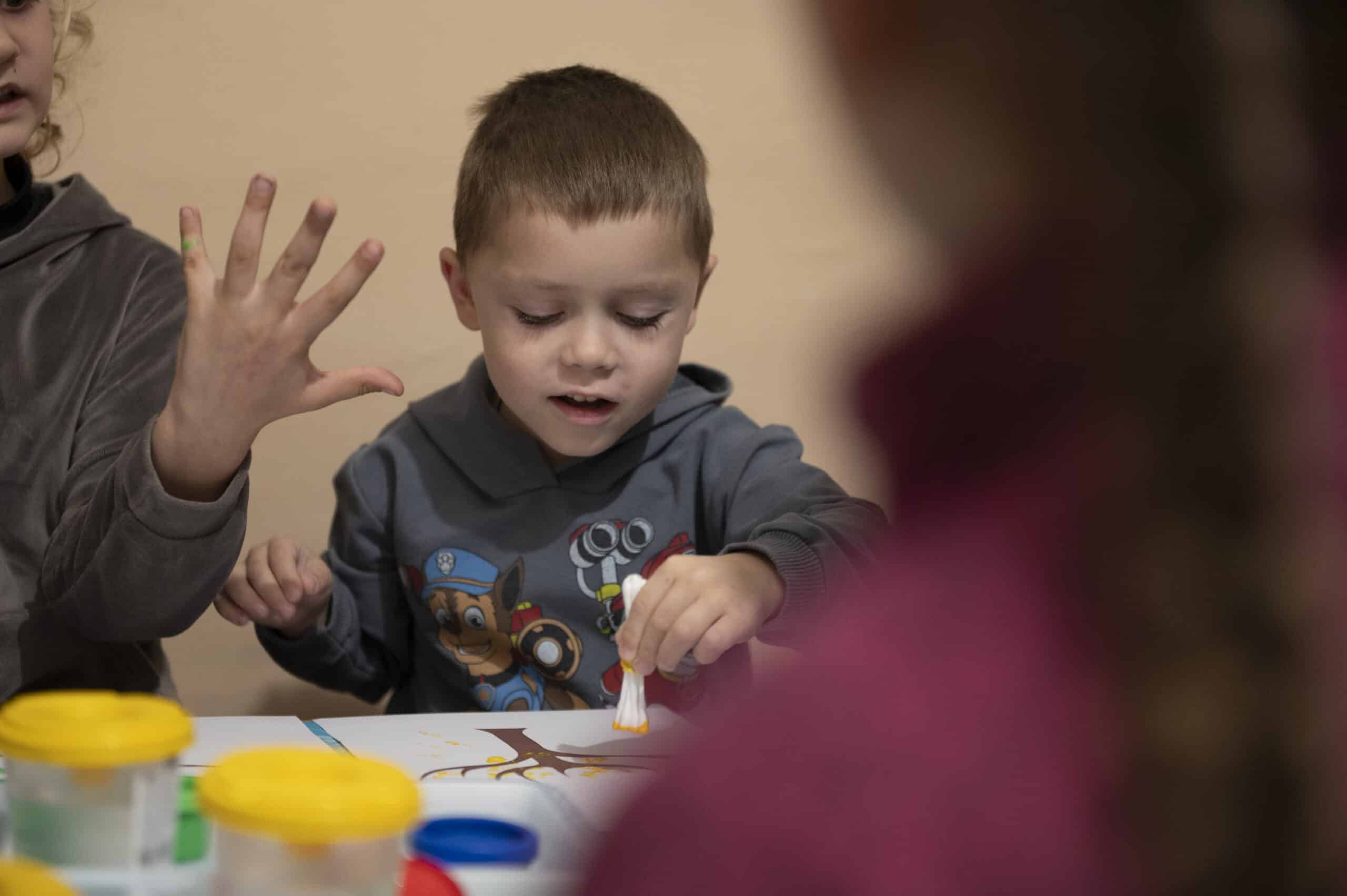 Vanya (5) sitter ved et bord og maler sammen med andre barn i et trygt rom i Tsjernihiv i Ukraina.