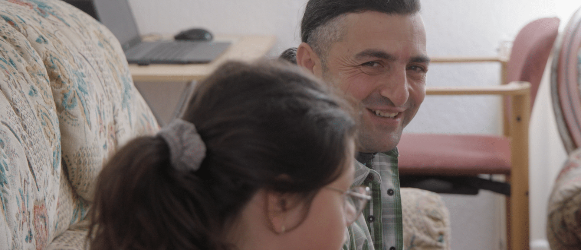 Dragan Arsić smiler til en av døtrene sine hjemme i familiens stue i Gračanica, Kosovo.