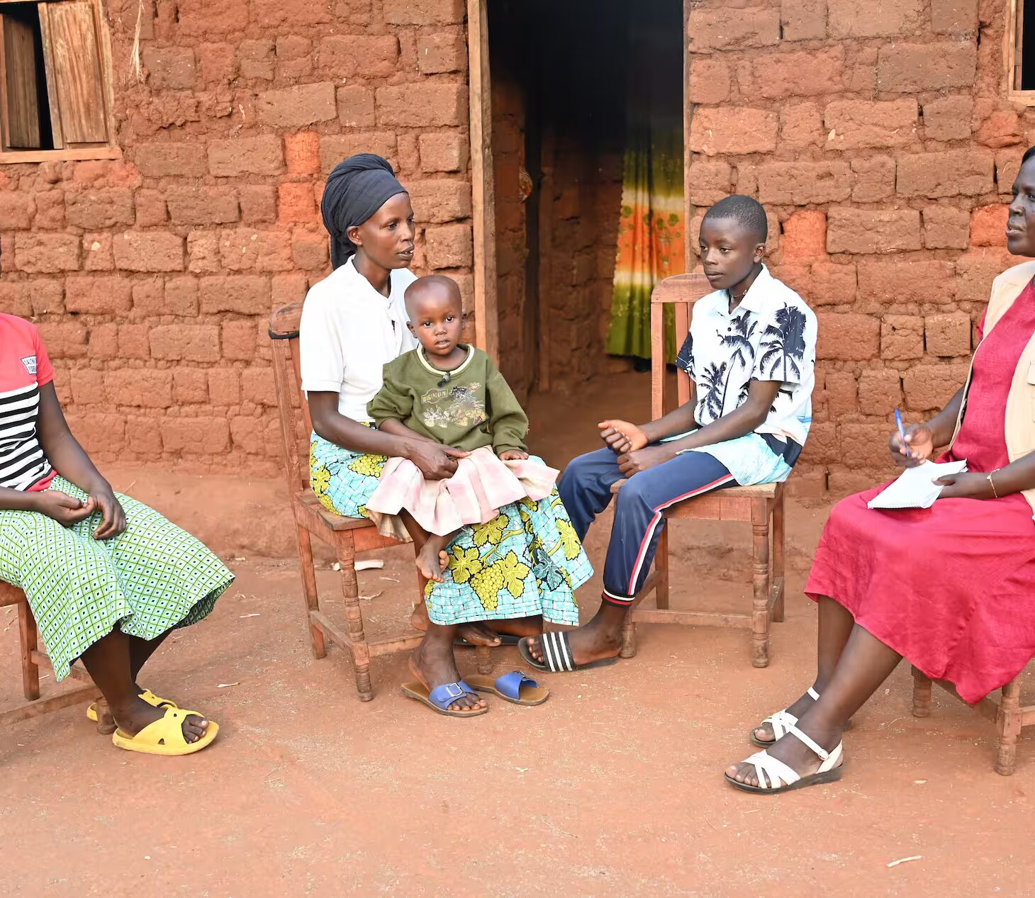 Charlotte sammen med familien og sosialarbeideren utenfor hjemmet sitt i Burundi. Foto: SOS-barnebyer