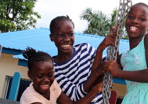 Barn som smiler og leker i en lekeplass. Foto: SOS-barnebyer
