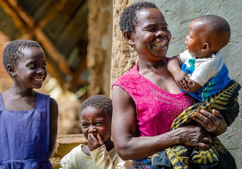 Mor med tre barn, hun har den lille babyen i armene og de to eldste barna smiler. Fra familieprogrammet i Blantyre, Malawi. Illustrasjonsfoto: Cornel van Heerden