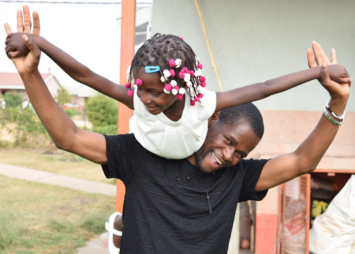 Silva med ei lita jente på skulderen. Han er en av sosialarbeiderne i barnebyen, og kalles "Storebror" av barna. Foto: Roger Heimli