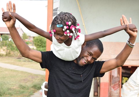 Silva med ei lita jente på skulderen. Han er en av sosialarbeiderne i barnebyen, og kalles "Storebror" av barna. Foto: Roger Heimli