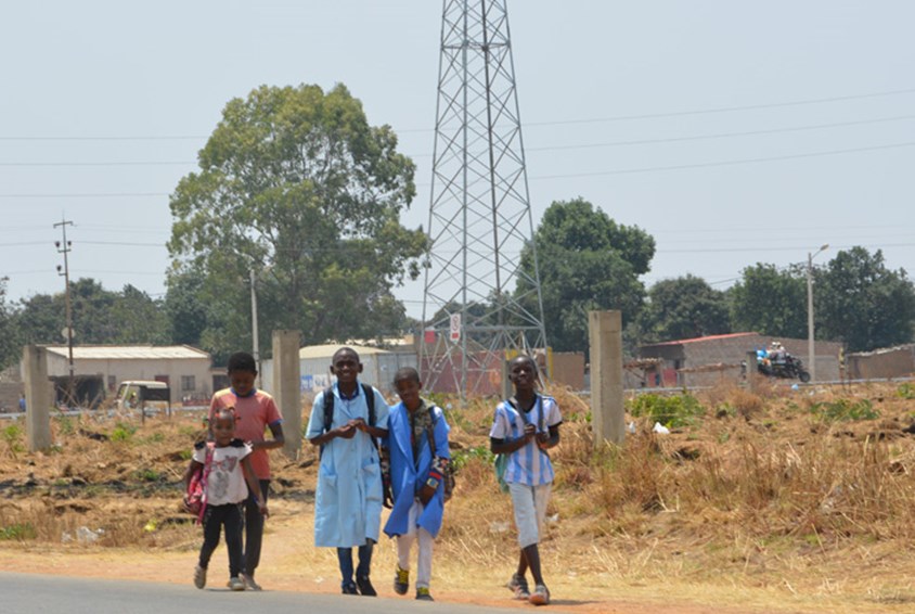 Barna på vei til skolen. Elektrisitetsmaster i bakgrunnen. 