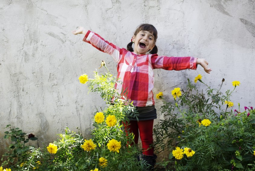 Det skal ikke mye til for å glede et barn. Et ball å leke med, er tre å klatre i, eller bare en vakker blomstereng å stå i. Foto: Nina Ruud