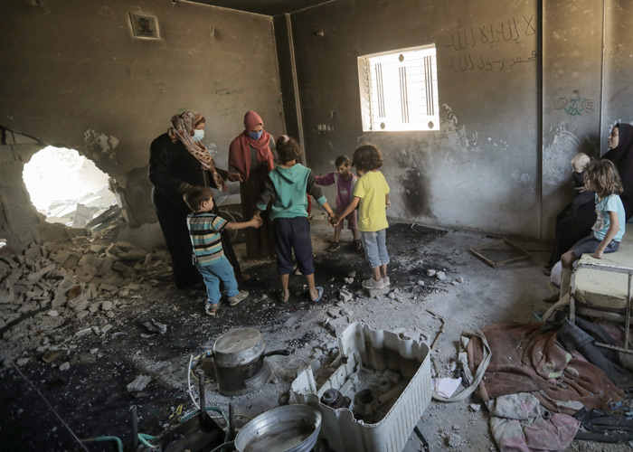 Familien står inne i huset, det er et stort hull i veggen. Foto: Loay AlSawafeery