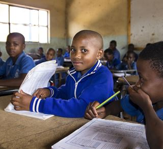 Elever i blå skoleuniformer sitter ved pultene sine i en skole i Eswatini.
