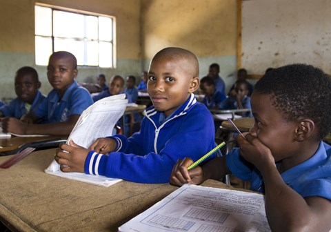 Elever i blå skoleuniformer sitter ved pultene sine i en skole i Eswatini.