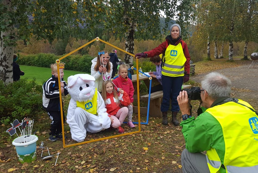 Barn og kanin i fotoramme og fotografen sitter til høyre i gul vest og tar bilde.