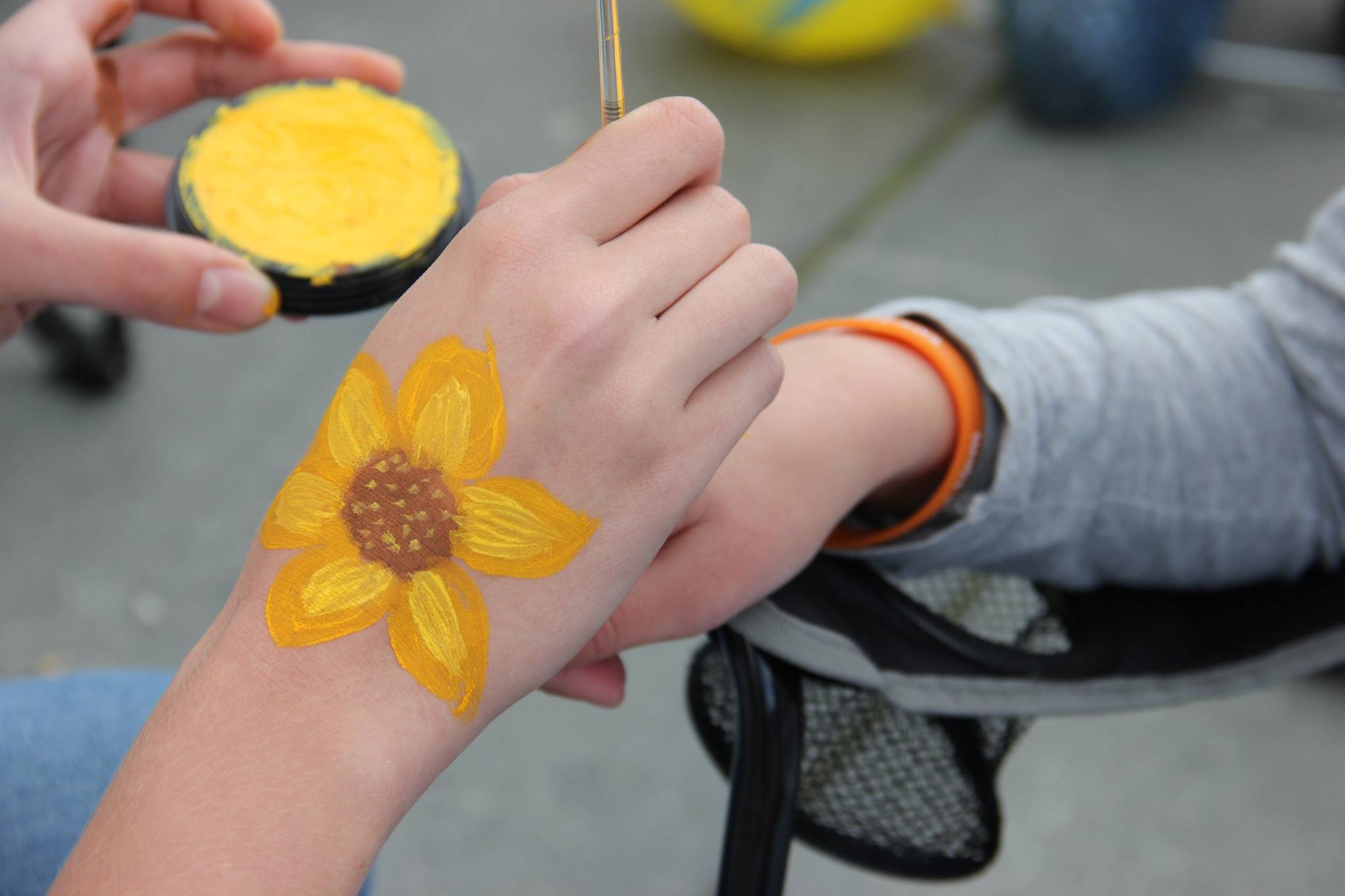 Nærbilde av hånd med solsikke på maler solsikke på en annen hånd.
