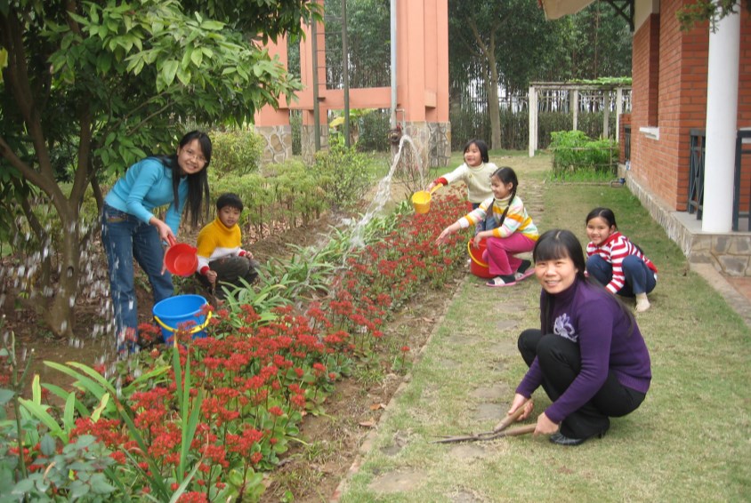 Barna i barnebyen hjelper til med familiens hagearbeid.