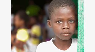 Portrett av alvorlig gutt fra Haiti, med hvit t-skjorte. Foto: SOS-barnebyer