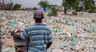 Jordskjelvet har ført til store ødeleggelser. En ung gutt står med ryggen til og ser ut over ruinene av hus. Foto Danielle Pereira