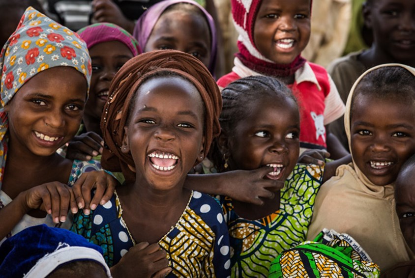 Glade barn i fargerike klær. De er med på aktiviteter som SOS-barnebyer arrangerer i en flyktningleir i Niger. Foto: Vincent Tremeau