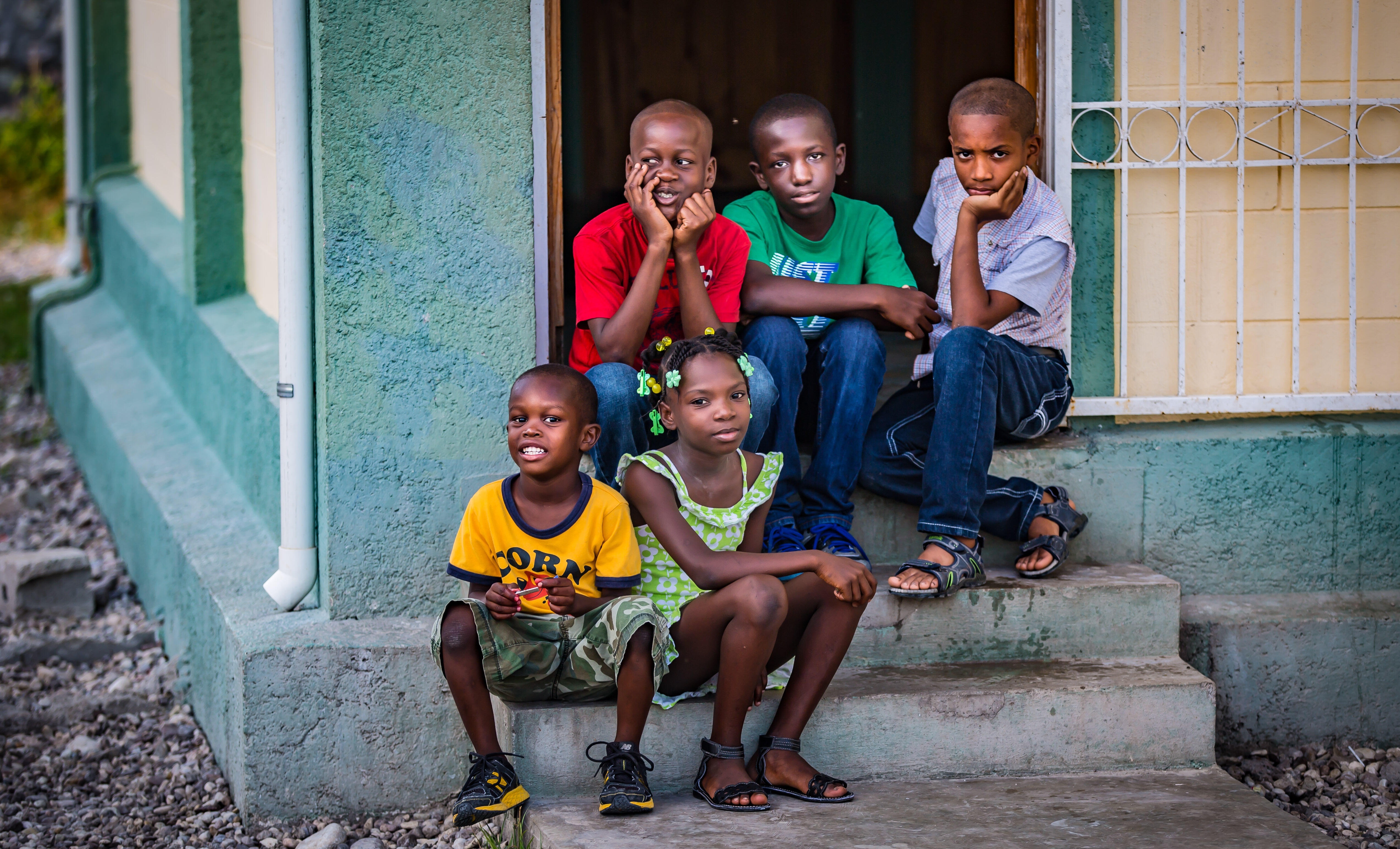 En gruppe barn sitter på trappa foran barnebyen. Foto: Maxence Bradley