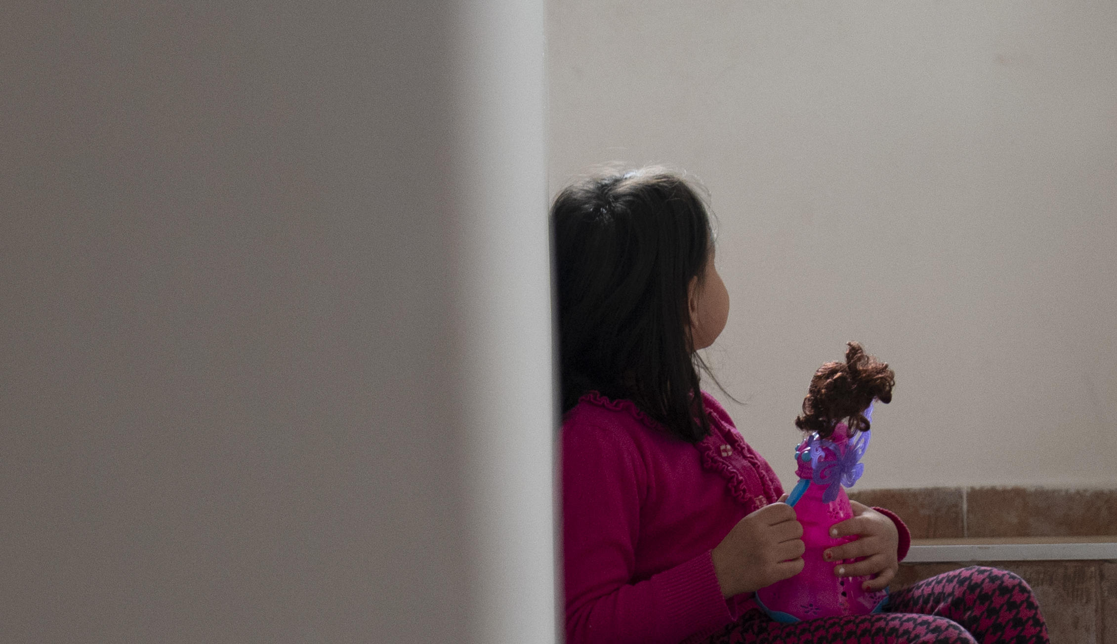 Lita jente lener seg inntil en vegg og holder dukken sin i hånda. Foto: Katerina Ilievska