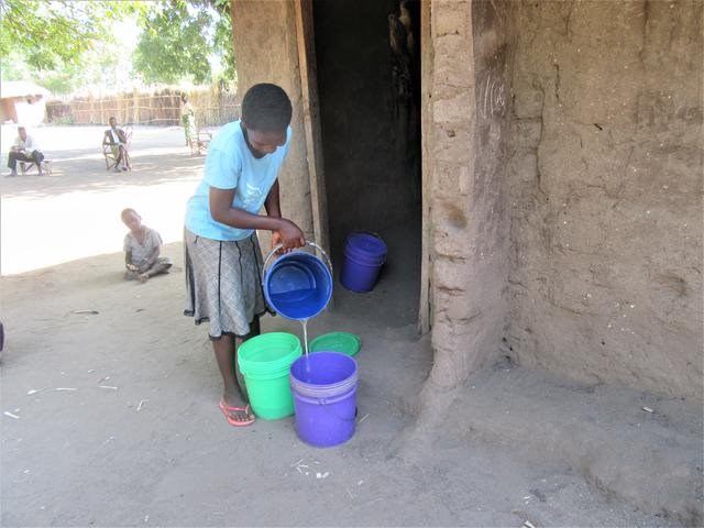 Kozani utenfor huset til familien. Hun fyller vann i bøtter.
