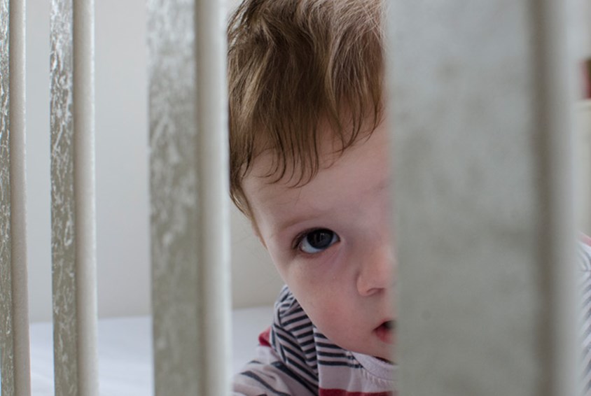 Et lite barn titter mellom sprinklene i en seng. Illustrasjonsfoto Katerina Iliveska

