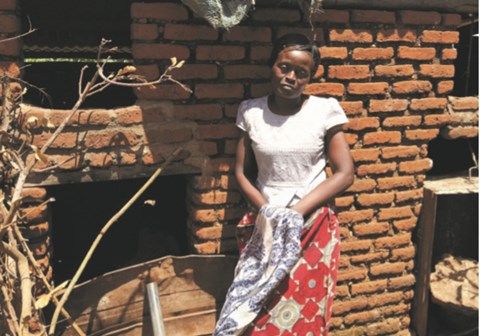 Agnes står inntil veggen på det nye huset. Foto: SOS-barnebyer