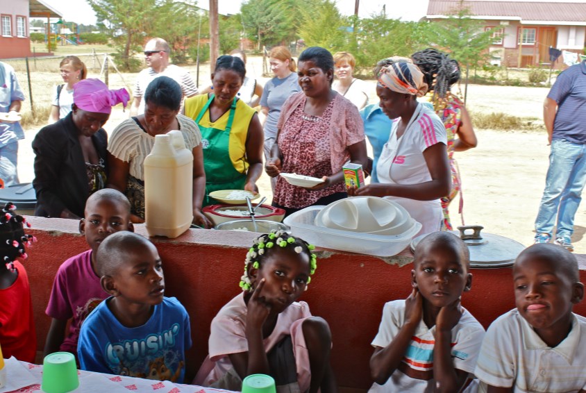 Barna venter tålmodig mens SOS-mødrene og tantene i barnebyen forbereder til felles lunsj. Foto: Emma With