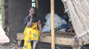 Jenta sitter i et ødelagt hus i Malawi. Foto: SOS-barnebyer Malawi