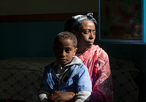 Mor med sønnen på fanget, hun sitter i et mørkt rom. Illustrasjonsfoto: Lars Just