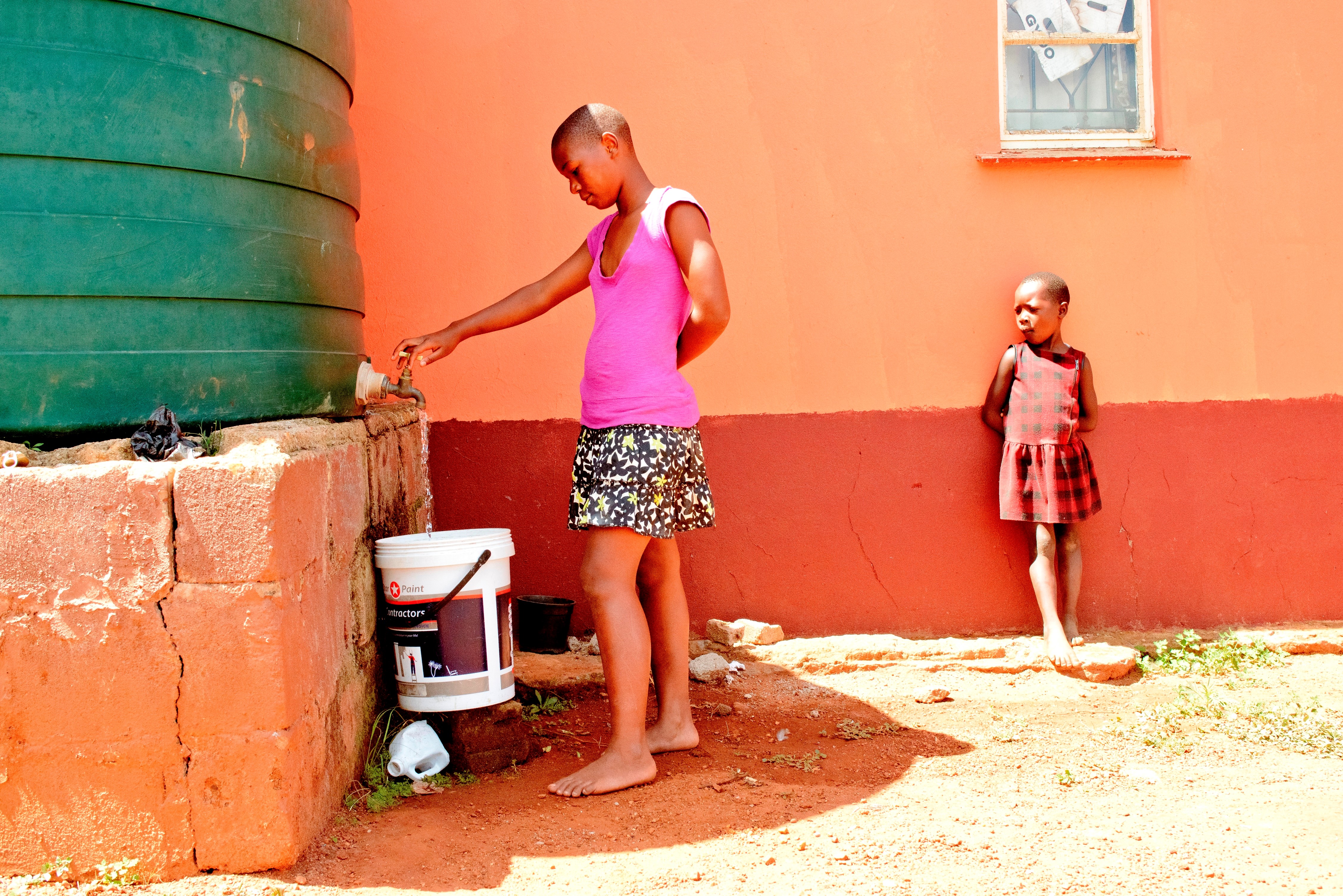 A girl from Mbabane's family strengthening program fetches water from their new harvesting tank. Photo: SOS Children's Villages