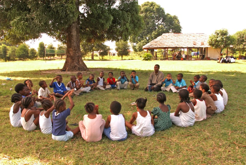SOS co-worker with children sitting in the grass SOS Children's Village Zanzibar, Tanzania