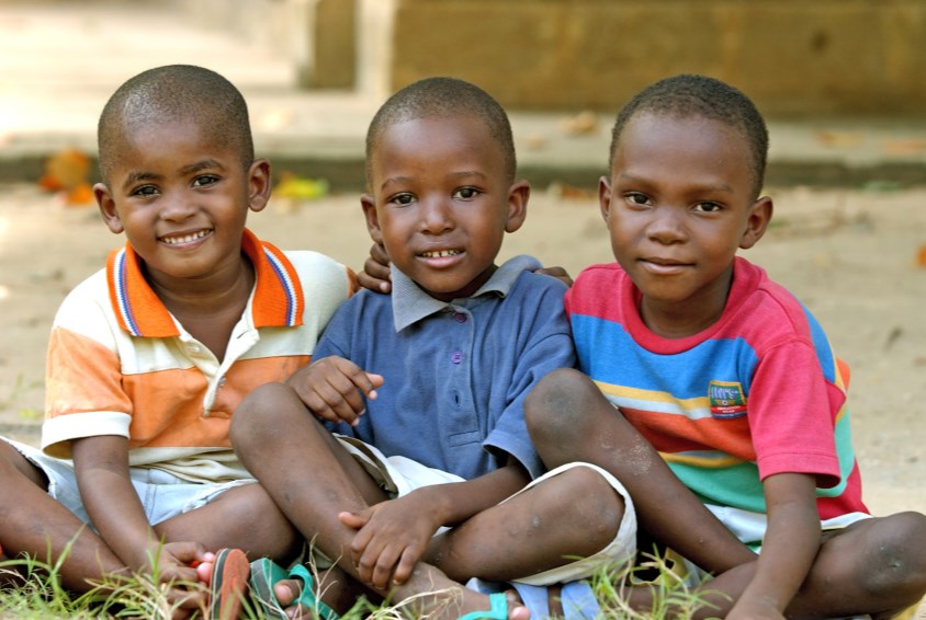 Three boys sitting in the grass SOS Children's Village Zanzibar, Tanzania Photo: Katja Snozzi