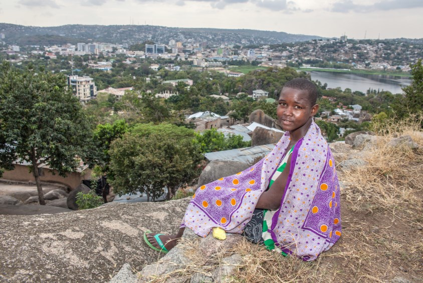 Salima (16) sitter på toppen av noen klipper i nabolaget sitt og ser ut over Mwanza. Foto: Bjørn-Owe Holmberg