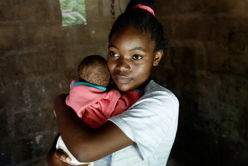 Babette har lille Noah i armene. Støtten Babette nå får gjennom SOS-barnebyers familieprogram i Zambia, gjør at hun nå klarer å studere, og være mor for lille Noah. Foto: Paul Audestad