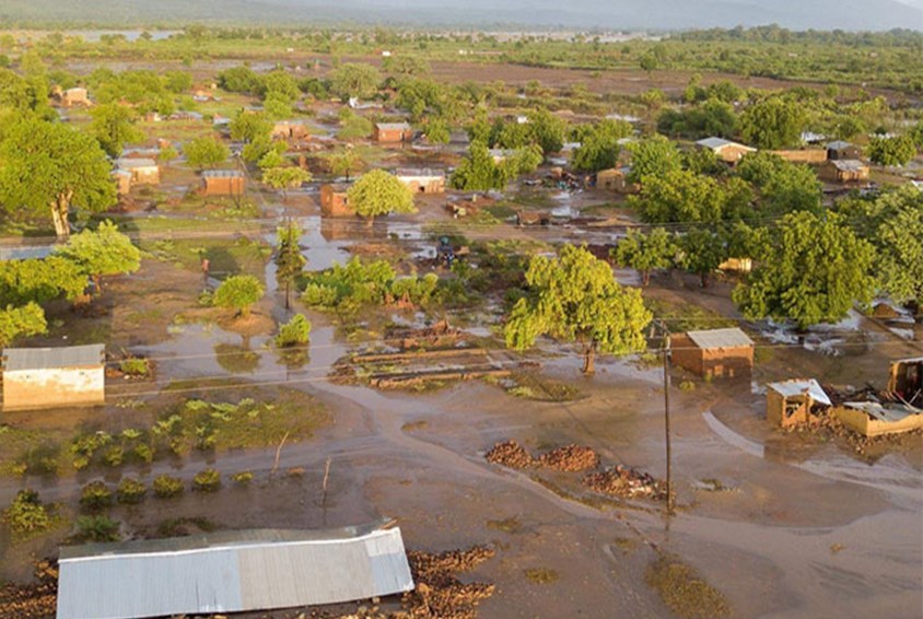 Bilde fra av et oversvømmet område, der vannet står over taket på noen hus. Foto: SOS-barnebyer