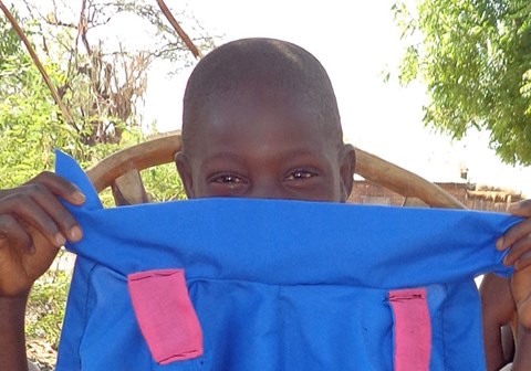 Gutt fra Ngabu holder ei blå jakke foran halve ansiktet, som moren hans har sydd. Illustrasjonsfoto fra Ngbu: SOS-barnebyer
