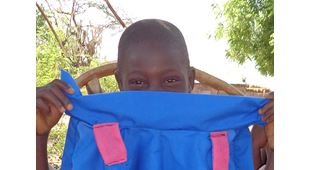 Gutt fra Ngabu holder ei blå jakke foran halve ansiktet, som moren hans har sydd. Illustrasjonsfoto fra Ngbu: SOS-barnebyer