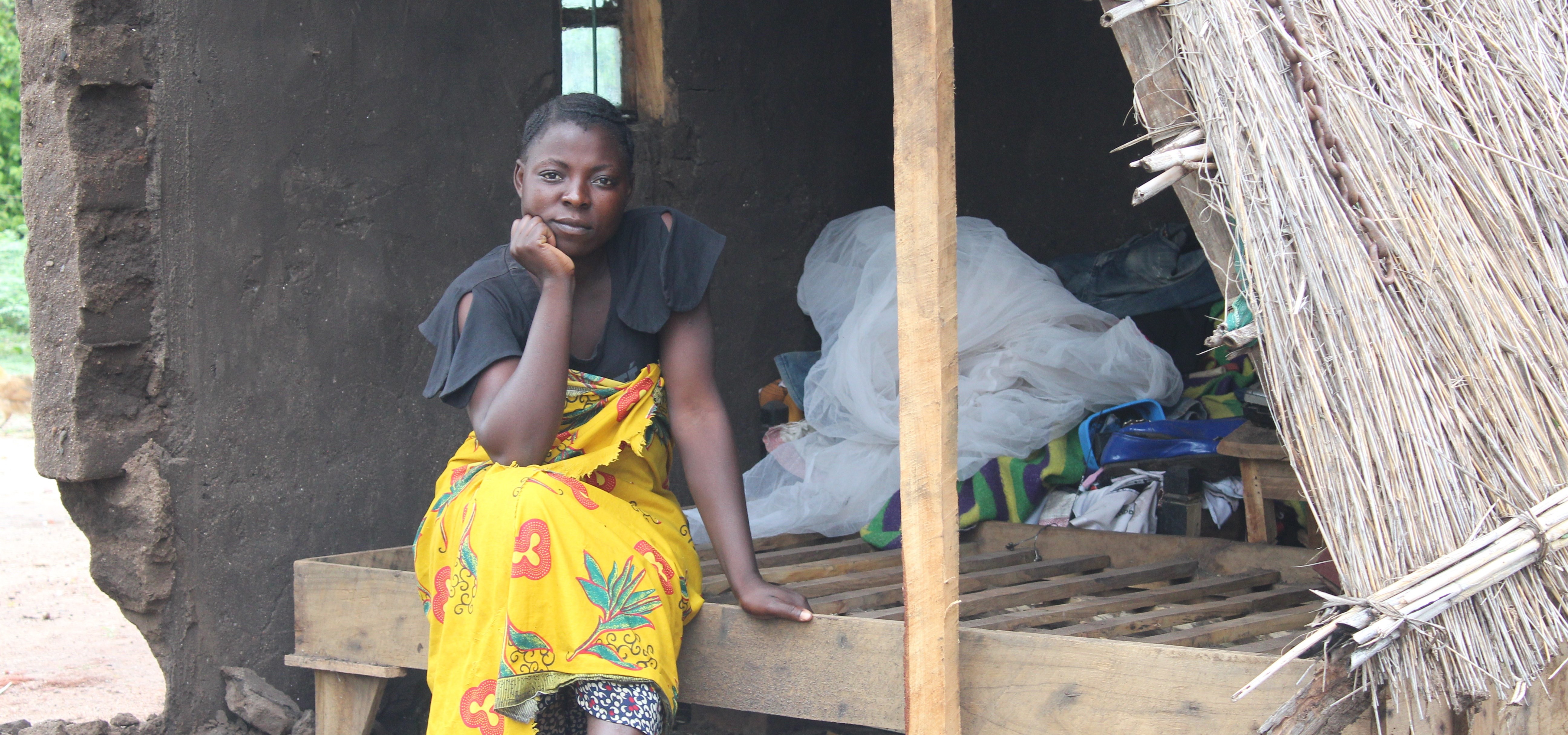 Jenta sitter i et ødelagt hus i Malawi. Foto: SOS-barnebyer Malawi